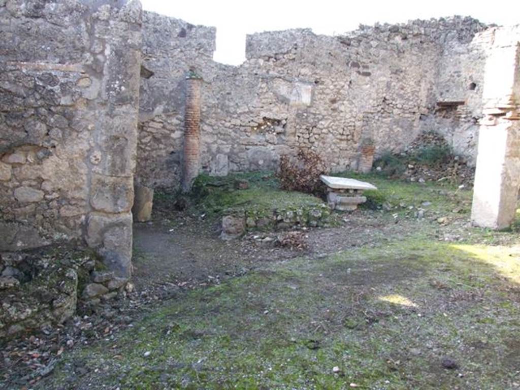 V.2.15 Pompeii. December 2007. Peristyle, looking west at remains of triclinium.
According to Jashemski –
“There was a narrow portico on the east supported by three columns which were joined by a low wall; the wider portico on the north in addition to the corner column was supported by a pillar. Between the corner column and the pillar stood a rectangular marble table mounted on two supports.
On the west, the garden was enclosed by a low wall which was shaped to leave room for the cistern-opening in the south-west corner. 
There was a gutter along the outer edge of the garden.
Built against the west wall was a masonry triclinium (l. medius, 4.20m; l . imus and l. summus, 3.30m; a rectangular table between the couches 0.93 x 0.57m).
It was shaded by a pergola supported by two columns in front, two engaged columns at the rear. 
The columns were covered in yellow stucco on which vines were painted. 
The holes in which the little poles which supported the vines were inserted are still visible.”
See Jashemski, W. F., 1993. The Gardens of Pompeii, Volume II: Appendices. New York: Caratzas. (p.111).