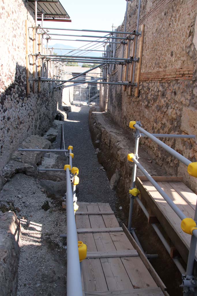 Vicolo dei Balconi, Pompeii. September 2021. Looking south between V.3, on left and V.2, on right. 
The entrance doorway to V.2.21 is on the right, where the sunlight is shining onto the planking.
Photo courtesy of Klaus Heese.