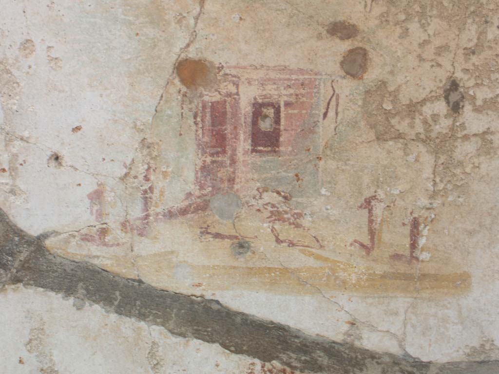 V.2.g Pompeii. May 2005. Room ‘e’, west wall with remains of painted central panel with painted rural shrine.
This west wall was also painted in a similar pattern to the north wall.
The pink zoccolo was scattered with red and white, with a central white panel containing the painting of the sacred landscape.
On either side were red side panels, all separated by narrow black bands (compartments).