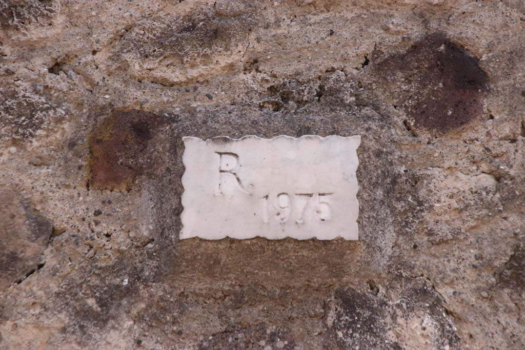 V.2.h Pompeii. September 2021. Plaque in wall on west of entrance doorway (R 1975) – Restored 1975. Photo courtesy of Klaus Heese.