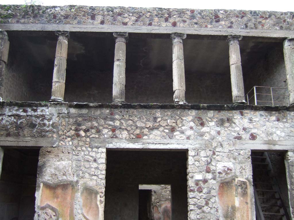 V.2.h Pompeii. December 2005. Upper floor cenaculum with columns, looking south across atrium.
According to NdS, in the atrium several parts of tufa fluted columns were found. 
They were of various sizes, with bases and Ionic capitals.
According to Sogliano, Mau believed that the said Ionic columns belonged to a portico above the rooms ‘e’, ‘f’ and ‘g’, which would have been open onto the rear side of the atrium.
In 1896 Sogliano thought this was certainly possible, as was seen in other places in Pompeii, but he would not confirm this with certainty, considering above all the lack of robustness of the supporting walls.
See Notizie degli Scavi di Antichità, 1896, (p.422).
See Mau in Bullettino dell’Instituto di Corrispondenza Archeologica (DAIR), VIII, 1893, (p.16)
By 1903, Sogliano agreed with Mau, as he wrote that “it was noted that above the tablinum and the two adjacent rooms was a portico or loggia open onto the atrium”.
See Sogliano in Atti del Congresso Scienze e Storiche, 19/4/1903, (p.322)