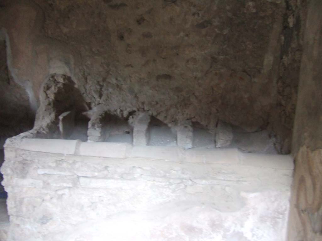 V.2.h Pompeii. December 2005. Kitchen ‘p’ in north-east corner of atrium, with hearth ‘2’, looking east.
According to Boyce, the lararium was on the south wall. 
On the right of the picture can be seen the remains of the lararium serpents.
See Boyce G. K., 1937. Corpus of the Lararia of Pompeii. Rome: MAAR 14. (p.37, no.107, Pl.17,2) 
To the left of the hearth was a latrine ‘1’.
