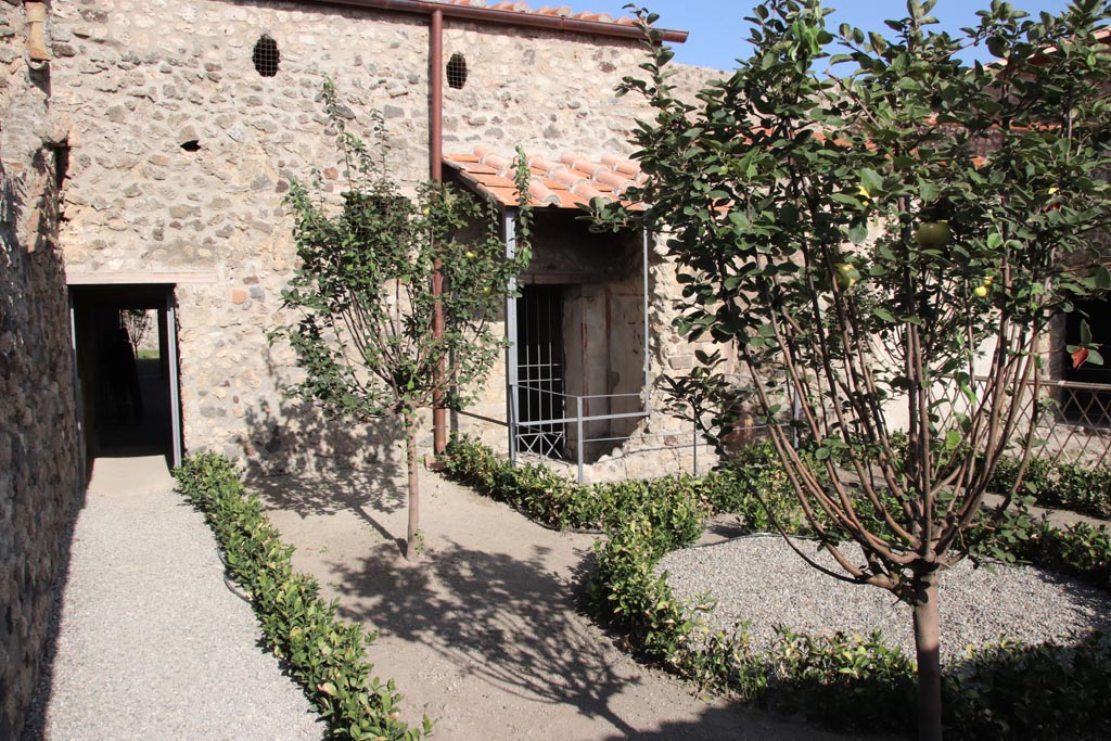 V.2.i Pompeii.  October 2023. 
Looking east across garden, with doorway to kitchen on left, and latrine in centre. Photo courtesy of Klaus Heese.