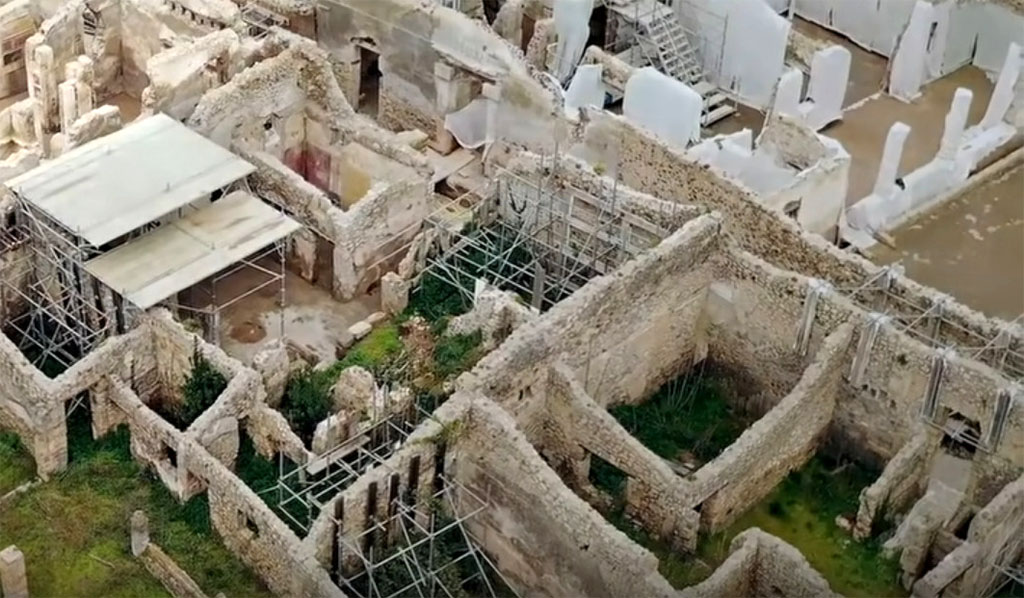 V.2.21 Pompeii. March 2020. Aerial view of excavations looking north-east across area with V.2.21, top left, and V.2.20, lower right. 
The newly excavated room A1 is top with the yellow and red walls, room A20 is to its left and room A9 further left, both under the protective roof.
Photograph © Parco Archeologico di Pompei.
See V.2.21 for further pictures.