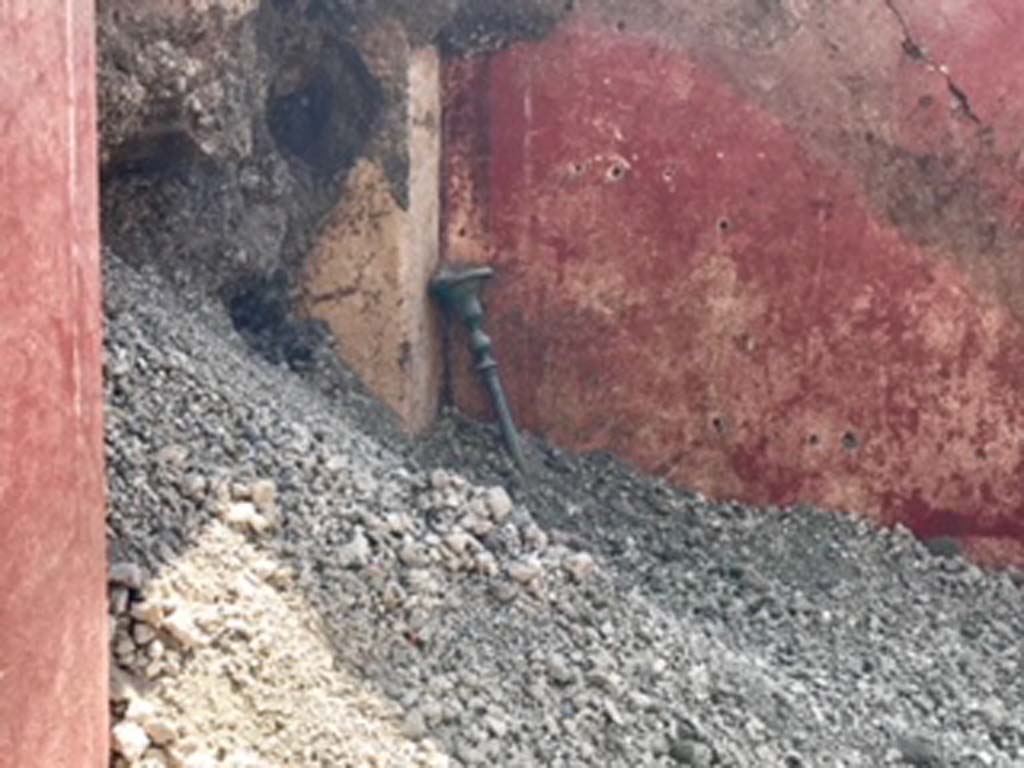 V.2.15 Pompeii. June 2018. Room A6 during 2018 excavations. Bronze candelabra by east wall doorway. 
Although already investigated by an exploratory trench and a tunnel dateable to the first modern investigations, in the corner of this room an elegant bronze candelabra was found, resting on the floor. 
Photograph © Parco Archeologico di Pompei.