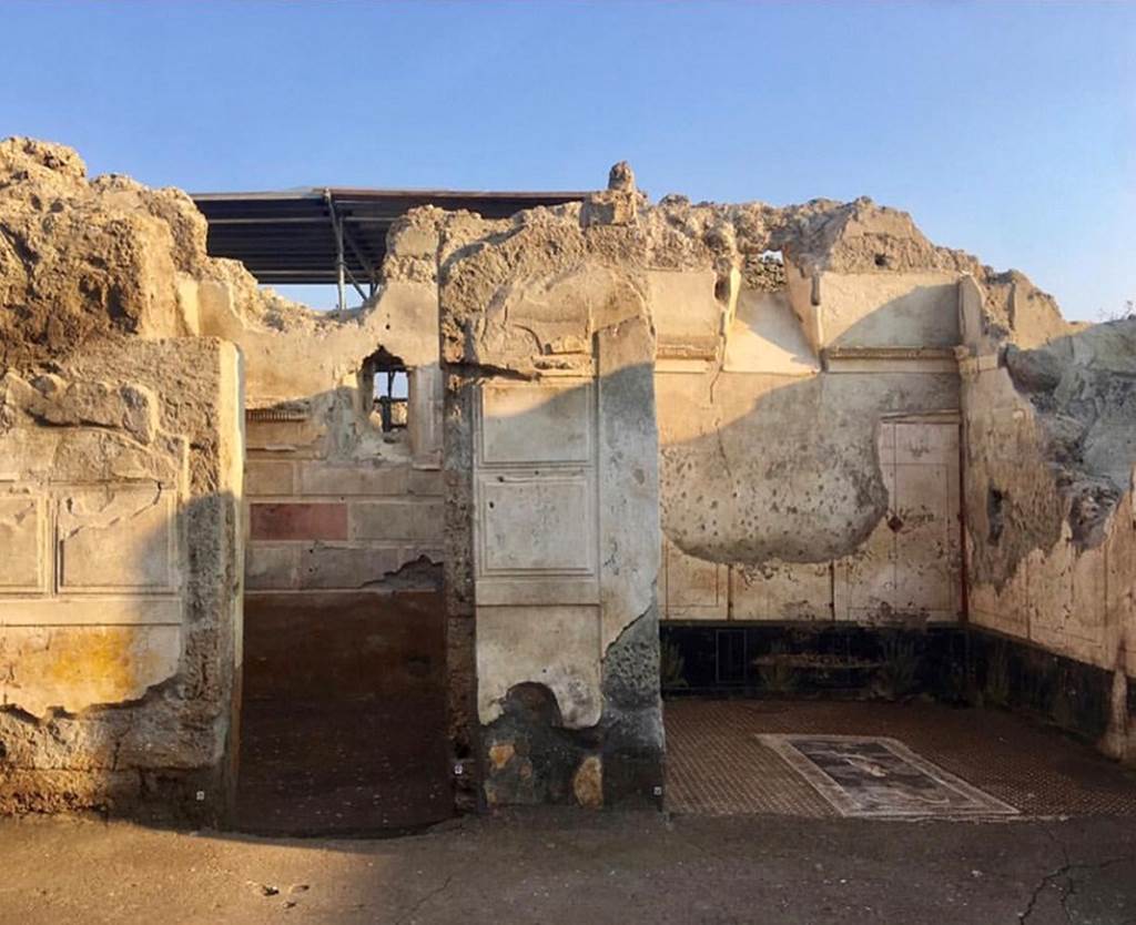 V.2.Pompeii. Casa di Orione. March 2019. 
Looking south across atrium towards doorway to room A11 (left) with first style decoration. 
Room A13, the south ala, is to the right.
Photograph © Parco Archeologico di Pompei.
The doorway to room A11 would have had a door (as shown by the two typical recesses visible along the jambs in parallel limestone blocks, just over a metre and a half above the ground level, functional to the lodging of the closing pole/stake/bolt, and a high window opening in the south wall which took light from an open area of the nearby House of Adonis (V.2.21).
This room would have been used as a cubiculum, although at the time of the eruption it may have been used for something else. 
The walls contained many holes (which together with hinges and iron nails found in the lapilli) indicated the presence of shelves and shelving, so possibly the room was being used as a storeroom. 
See Osanna M, 2019. Pompei. Il tempo ritrovato. Le Nuove Scoperte. Milano: Rizzoli (p. 100).