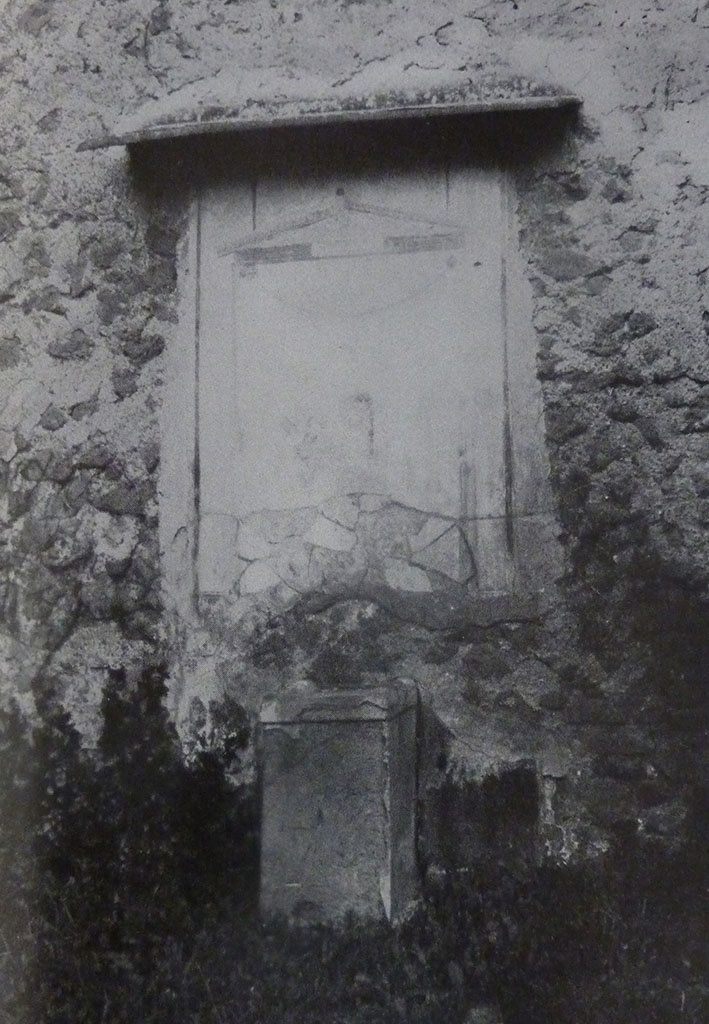 V.2 Pompeii. Casa di Orione. Old undated photograph. Garden 11c. North wall. Lararium.
The Notizie degli Scavi records a panel of white stucco.
On this is painted an aedicula, which Boyce says is painted in blue, yellow, dark red and green.
Within the aedicula is a painting of Giove (Jupiter) seated on a throne.
Underneath is a masonry altar covered with white plaster. 
See Notizie degli Scavi di Antichità, 1894, p. 439.
See Boyce G. K., 1937. Corpus of the Lararia of Pompeii. Rome: MAAR 14.  (96, p.35, Pl 39,3).