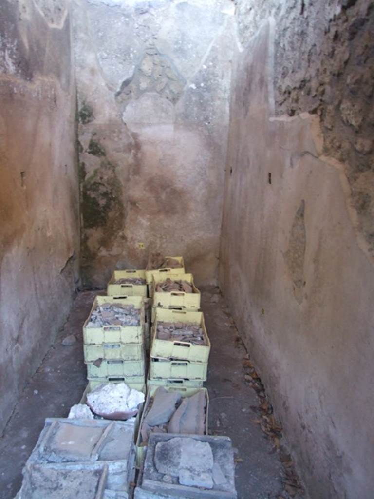 V.3.4 Pompeii. March 2009. Small room with remains of shelving supports. According to Sogliano, the small room on the south side of the end of the corridor was covered with a roof. The roof tilted outwards, and some roof tiles remained in situ. The flooring was of broken brick pieces, and the walls covered with rough plaster, with high brick plinth. Found in the east and west walls, at a height of 1.20m from the flooring, were three square holes for each wall. These holes were decorated with a yellow band around them, and were intended to hold the wooden shelving supports. However as there was no trace of either on the walls, he believed they had not yet been put into place. See Notizie degli Scavi di Antichità, 1905, (p. 209-10)