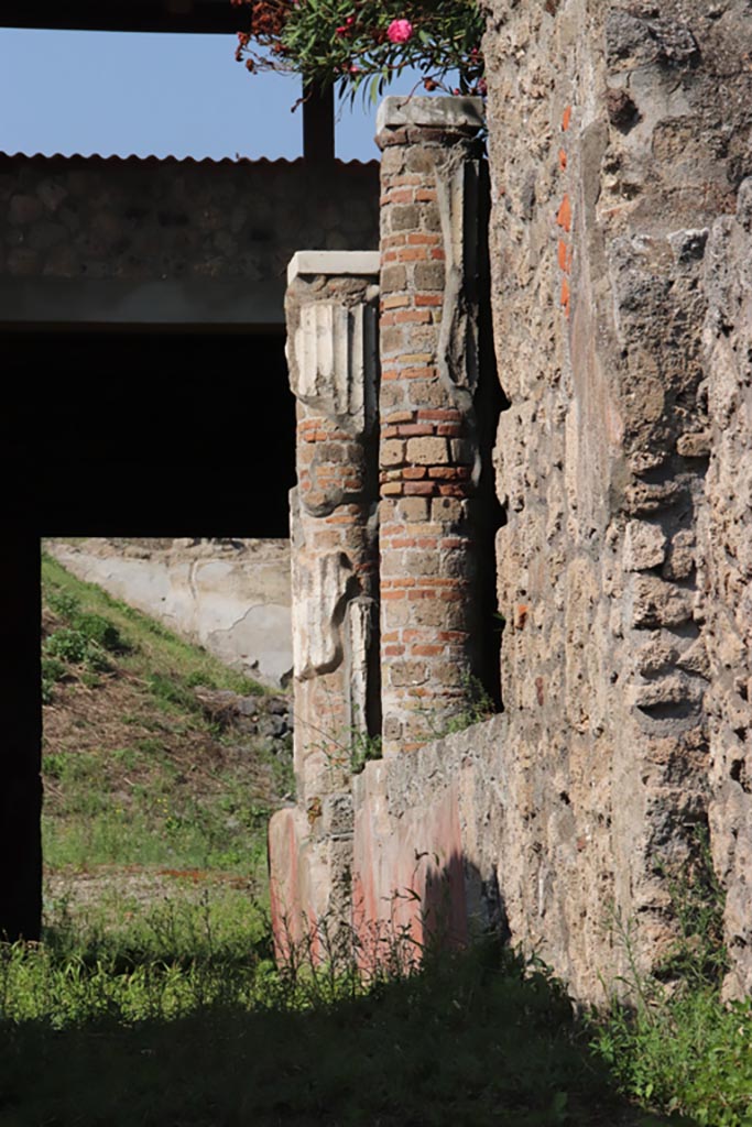 V.3.4 Pompeii. October 2023. 
Looking north from entrance doorway towards two white stuccoed columns on west side of garden, which supported the west and partial north portico.
Photo courtesy of Klaus Heese.