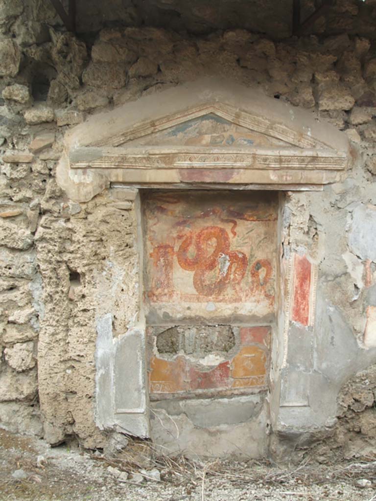 V.3.7 Pompeii. May 2005. West wall of garden area. Large aedicula lararium.
The pediment extends far beyond the supporting pilasters on each side.
The rear of the lararium has upper and lower zones which were divided by a partition.
See Boyce G. K., 1937. Corpus of the Lararia of Pompeii. Rome: MAAR 14.  (112, p. 38, Pl 36, 2).
