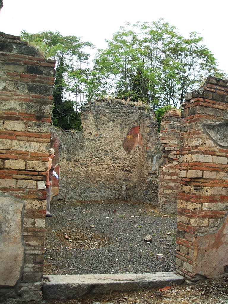 V.3.9 Pompeii. May 2005. Entrance doorway, looking west.
According to NdS, the entrance threshold stone was made of lava, and led into a poor little house of modest appearance.
The door jambs were brick and opened immediately into the atrium.
In the corner, to the left of the doorway as one entered, was a cistern with a terracotta puteal in which it seemed the rainwater would have emptied by a clay pipe, now disappeared. The puteal was covered with stucco, coloured red.
The impluvium had been eliminated in a make-over of the house, however traces of it can be seen in the flooring of the atrium.
The floor of the atrium was decorated with triangular pieces of different marbles.
See Notizie degli Scavi di Antichità, 1902, dated November 1901, p.201-203.