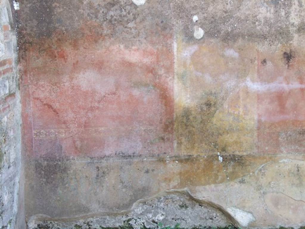 V.3.9 Pompeii. March 2009. West wall of site of room in the south-west corner. According to NdS, the west wall was decorated more lavishly than  the others. In the area above the yellow dado, the wall was divided into three panels, red on either side of a yellow panel.
The central yellow panel showed a painted closed door on which was a painted door-ring with a tiger’s head with the ring in its mouth. The two red side panels each contained a medallion of a maritime landscape, with boats, and fishermen, on the banks were porticoes, temples, statues, etc. Above the yellow central panel was painted a small but beautiful sea-battle.  Above that was a painted eagle with wings, and lightning between its claws. Around the eagle on the upper zone of the wall, were painted representations of architectural motifs, and two flying griffins, their tails ending in painted scrolls and plants. Under their legs were two dolphins.
See Notizie degli Scavi, 1902, dated November 1901, p.201-203