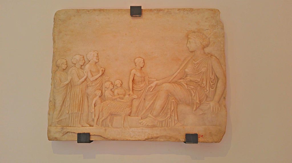 V.3.10 Pompeii. 2016/2017. Marble relief showing a goddess, most likely Aphrodite, enthroned on a rock. (Late 5th-Early 4th Century BC).
Found on 12th September 1901, in the small garden, not in situ but leaning against the western wall. Photo courtesy of Giuseppe Ciaramella.