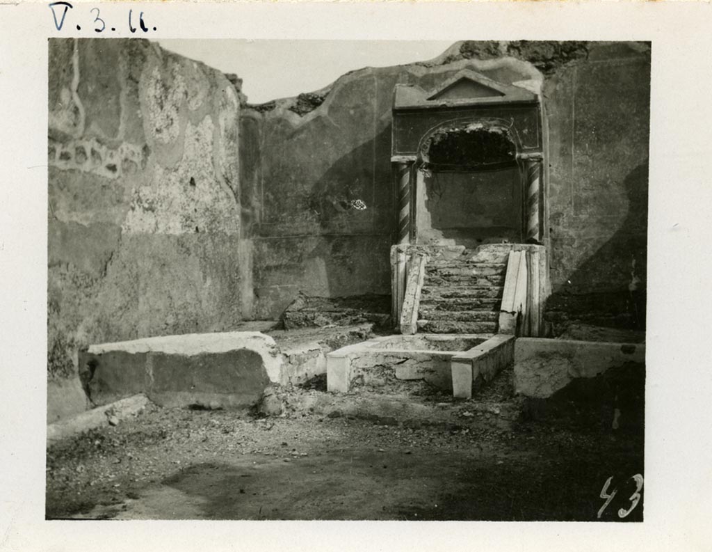 V.3.11 Pompeii. pre-1937-1939. Looking towards south wall of the garden with aedicula fountain niche, pool and biclinium. 
Photo courtesy of American Academy in Rome, Photographic Archive. Warsher collection no. 437.
According to Jashemski –
On the south wall of the small garden (excavated in 1902), there was an aedicula-shaped fountain niche with a masonry couch on either side 
(l. imus and l. summus, 3.00m). There was a crudely painted garden painting above each couch.
Water, perhaps from a statuette carried away in antiquity which stood in the aedicula, ran down the little steps into the rectangular pool below.
The front of the pool was concave, parallel to the curve of the niche; the back of the pool in front of the water-steps was shaped in the same way. 
A jet rose in the centre of the pool. There was a planted area on each side of the pool. 
A mask, intended for use as a fountain, was found in a room off the atrium.
Jashemski sources –
Parabeni, N.Sc, (1902), p.276, 371, 372 (the plan opposite p.369 gives the location of the pipes that carried water to the two fountains in the garden);
Thedenat, p.87.
Soprano, p.306, no.27.
Neuerburg, p.122-23, no.24.
Dohl, p.13.
Dwyer, "Oscilla”, p.279, no.83.
See Jashemski, W. F., 1993. The Gardens of Pompeii, Volume II: Appendices. New York: Caratzas. (p.115).