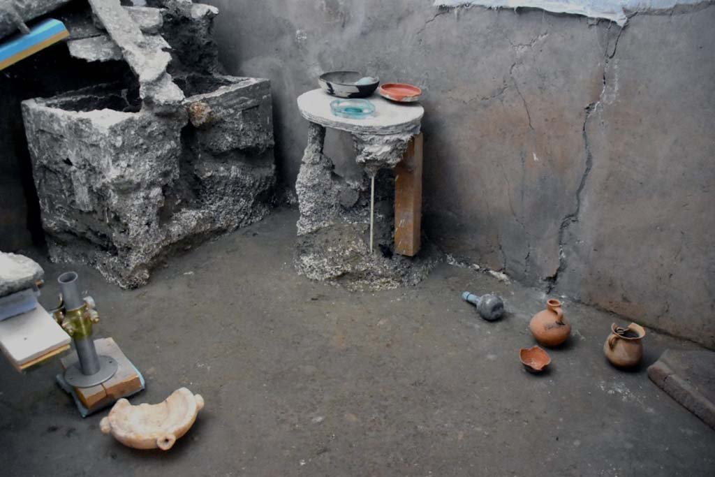 V.3.13 Pompeii. 2022. Room 3b, bedroom.
Next to the chest was a small, circular three-footed table, upon which was a ceramic cup containing two glass ampoules, a small sigillata plate and another small glass plate. At the foot of the table, a glass ampoule as well as small jugs and amphorae testify to the everyday use of the room. The furniture and ceramic vessels were found in the position they must have been left in when the owners fled, giving us a snapshot of that moment.
Accanto ad esso, un tavolino circolare a tre piedi con sopra ancora una coppa in ceramica contenente due ampolline in vetro, un piattino in sigillata ed un altro piattino in vetro. Ai piedi del tavolino, un’ampolla in vetro e brocchette ed anforette che testimoniano un uso quotidiano della stanza. Il mobilio e le forme ceramiche sono stati trovati nella posizione in cui dovevano essere nel momento della fuga, restituendoci una fotografia di quell’istante.
Photograph © Parco Archeologico di Pompei.