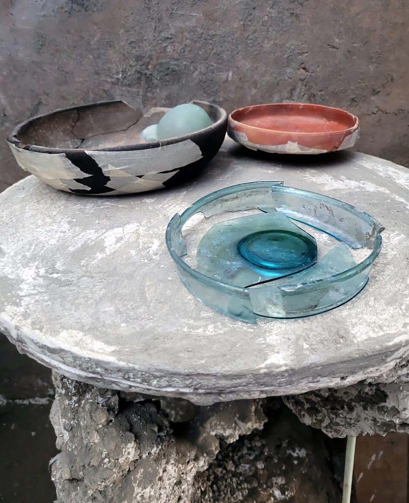 V.3.13 Pompeii. 2022. Room 3b, bedroom.
Next to the chest was a small, circular three-footed table, upon which was a ceramic cup containing two glass ampoules, a small sigillata plate and another small glass plate.
Accanto ad il baule c’era un tavolino circolare a tre piedi con sopra ancora una coppa in ceramica contenente due ampolline in vetro, un piattino in sigillata ed un altro piattino in vetro.
Photograph © Parco Archeologico di Pompei.