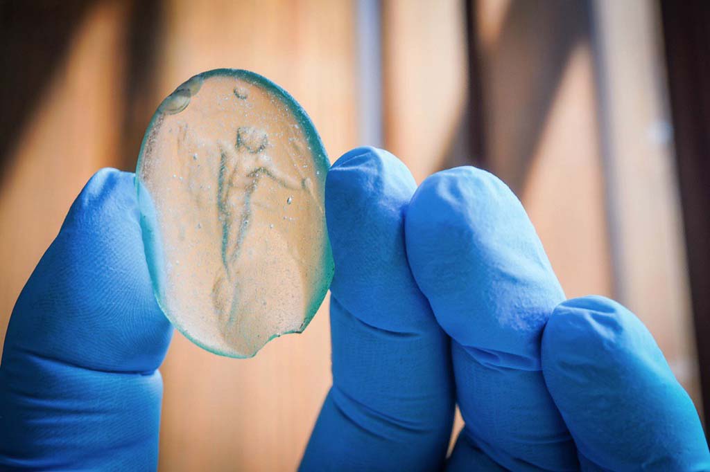 V.3 Pompeii. Casa del Giardino. August 2019. Amulet with naked figure.
Amuleto con figura nuda.
Photograph © Cesare Abbate/ANSA courtesy Parco Archeologico di Pompei.