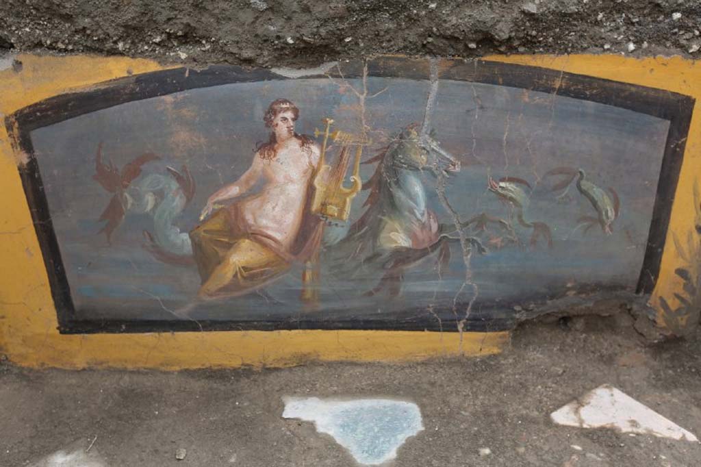 V.3 Pompeii. March 2019. The richly decorated Thermopolium in the open space which acts as a crossroads between Vicolo delle Nozze d’Argento and Vicolo dei Balconi. 
Painting of the beautiful figure of a Nereid holding a lyre, sitting on a marine horse with two dolphins swimming at the side.
V.3 Pompei. Marzo 2019. Termopolio all'incrocio tra il Vicolo delle Nozze d'Argento e il Vicolo dei Balconi.
Dipinto della bella figura di una Nereide che regge una lira, seduta su un cavallo marino con due delfini che nuotano ai lati.
Photograph © of Parco Archeologico di Pompei.