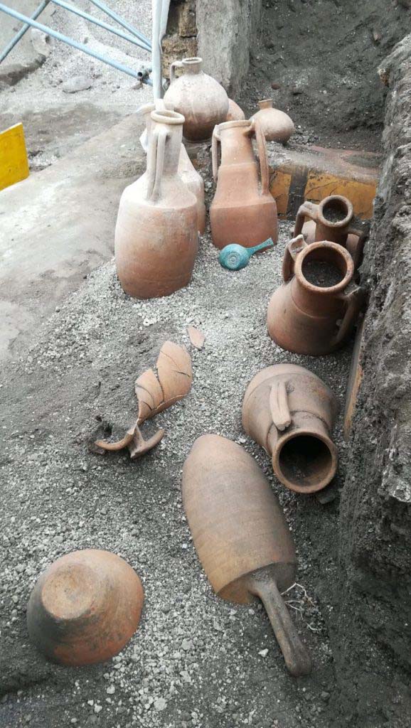 V.3 Pompeii. March 2019. 
Thermopolium at the crossroads between Vicolo delle Nozze d’Argento and Vicolo dei Balconi. 
The discovery of amphorae located in front of the counter, a bronze measure/pan and jars on top of the counter.
In the Thermopolium, various pantry and transport materials were discovered, including: nine amphorae, a bronze patera, two flasks and a common ceramic table olla. 
V.3 Pompei. Marzo 2019. Termopolio all'incrocio tra il Vicolo delle Nozze d'Argento e il Vicolo dei Balconi.
La scoperta di anfore situate davanti al bancone, una misura / padella in bronzo e vasetti in cima al bancone.
Nel termopolio è stato rinvenuto diverso materiale da dispensa e da trasporto: nove anfore, una patera di bronzo, due fiasche, un'olla di ceramica comune da mensa. 
Photograph © Parco Archeologico di Pompei.