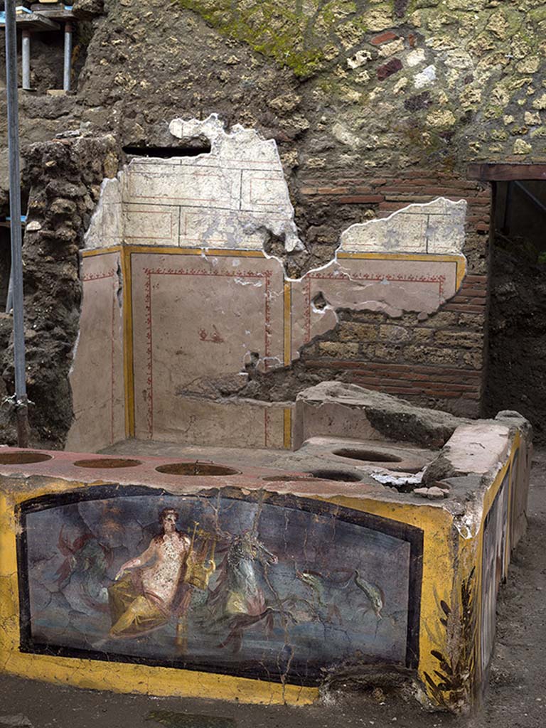 V.3 Pompeii, Thermopolium with painting of nereid. December 2020. Wall behind the counter decorated with panels bordered in yellow with imitation blockwork above.
V.3 Pompei, Termopolio con dipinto di nereide e anfore. Dicembre 2020. Parete dietro il bancone decorata con pannelli delimitati in giallo con imitazione di blocchi sopra.
Photo by Luigi Spina courtesy of Parco Archeologico di Pompei.