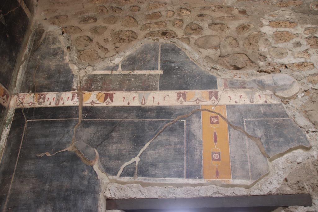 V.4.a Pompeii. October 2023. 
Upper south wall of atrium in south-east corner, detail of painted decoration above doorway to room ‘g’. Photo courtesy of Klaus Heese.