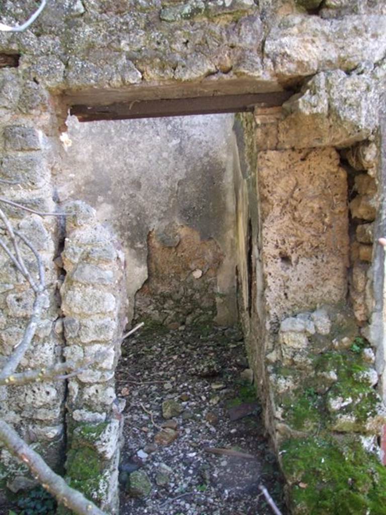 V.4.c Pompeii. March 2009. Doorway to kitchen, or rustic room M, on south side of garden.
The doorway had its threshold and door jambs of wood: except to the right where the doorpost of wood was later replaced with very rough plaster. From the many holes in the walls and some remains of iron nails, Sogliano thought this was probably a storeroom. 
Covered by an attic floor, it received light from a window overlooking the garden.