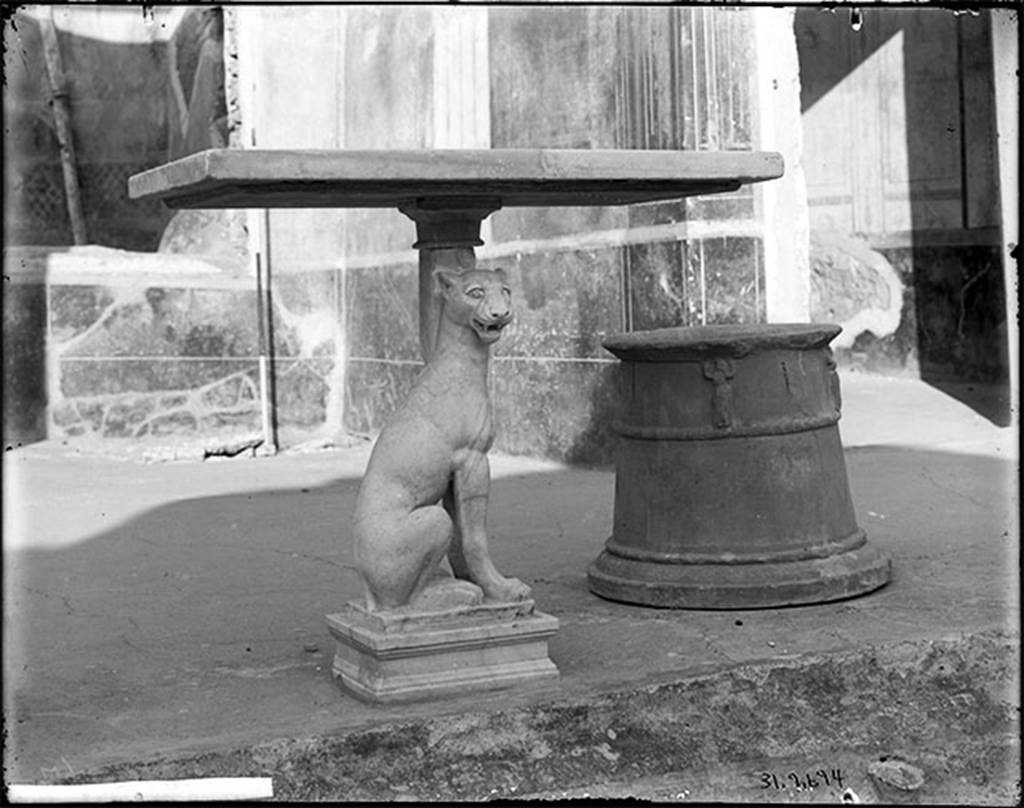 V.4.c. Pompeii. Atrium. Marble table with support in the form of a crouching panther. 
The panther had eyes made of glass paste.
The terracotta cistern mouth has caryatids supporting the rim and dates from the Republican age.
DAIR 31.2694. Photo © Deutsches Archäologisches Institut, Abteilung Rom, Arkiv. 
See Carratelli, G. P., 1990-2003. Pompei: Pitture e Mosaici. Roma: Istituto della enciclopedia italiana, Vol. III, pp. 1035-6.