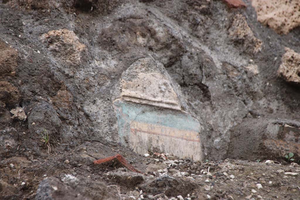 V.6.4 Pompeii. October 2020. Looking east to the decoration from the top of a wall, jutting from the excavated soil. Photo courtesy of Klaus Heese.