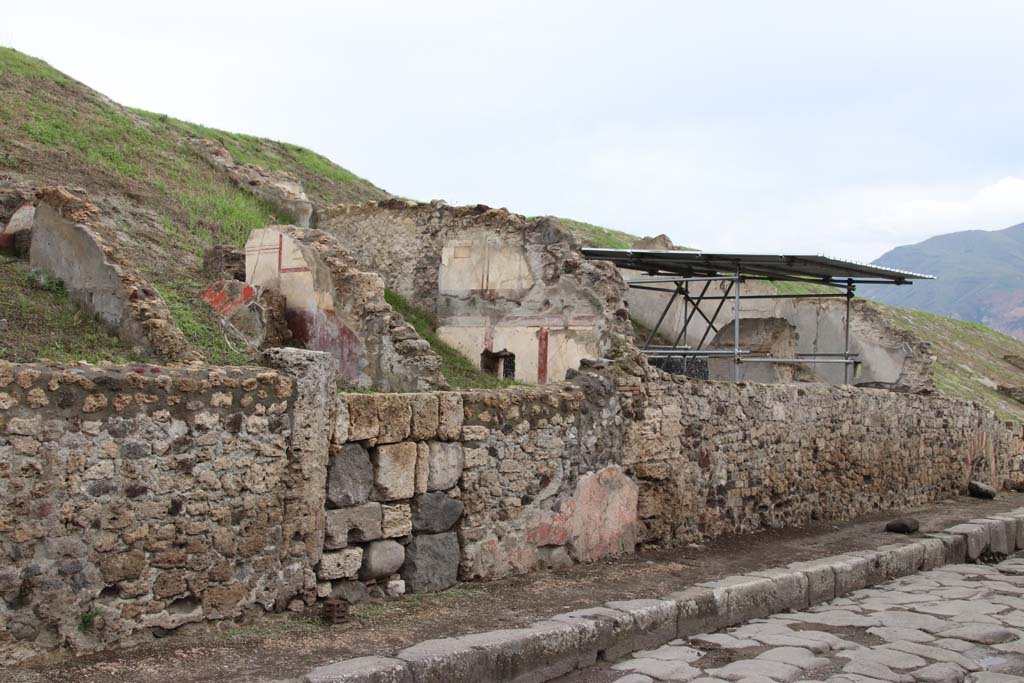 V.6.8 or 7 Pompeii, Pompeii. October 2020. Looking south along east side of Via del Vesuvio. Photo courtesy of Klaus Heese.
(Note: the roofed area where the lararium is seen above the wall, originally we had identified as V.6.7.
According to Massimo Osanna's book the lararium area is shown as casa 4 and the three front rooms to the north (left) is casa 3.
There does not seem to be a doorway entering the lararium area from this roadway or casa 3, so perhaps the numbered entrance doorway would be further at the rear, still buried. 
Therefore, perhaps the doorway with the large blocks in centre left, is now V.6.8.)
See Osanna M., 2019. Pompei. Il tempo ritrovato. Le nuove scoperte. Milano: Rizzoli, p. 216, fig. 4.