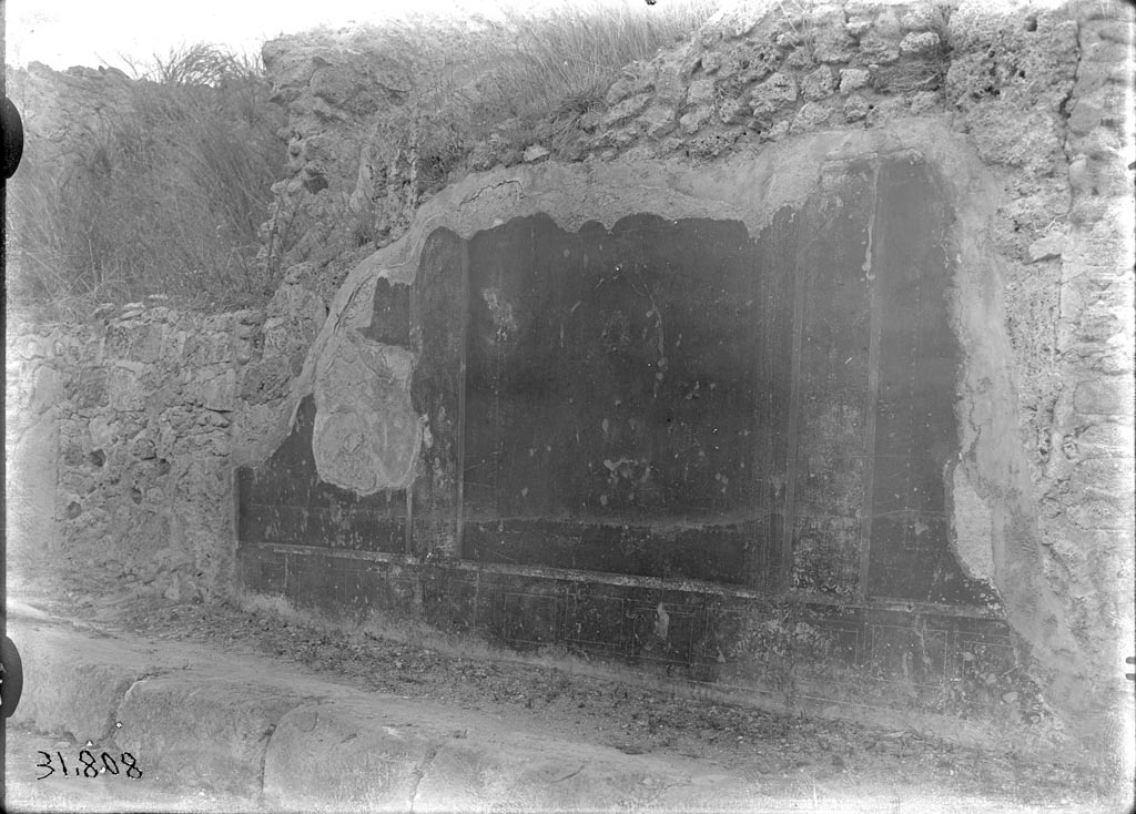 V.6.13 Pompeii. Geometric zoccolo and red panelled compartments on facade.
Comparison of the stonework with the photo above would seem to place this between V.6.13 and V.6.12.
V.6.13 room 39 is behind the bare stone wall on the left and V.6.12 room 7 is behind the painted wall area on the right.
DAIR 31.808. Photo © Deutsches Archäologisches Institut, Abteilung Rom, Arkiv. 
According to PPP, this photo was possibly from V.6.7 and V.6.6.
See Bragantini, de Vos, Badoni, 1983. Pitture e Pavimenti di Pompei, Parte 2. Rome: ICCD, p. 104.