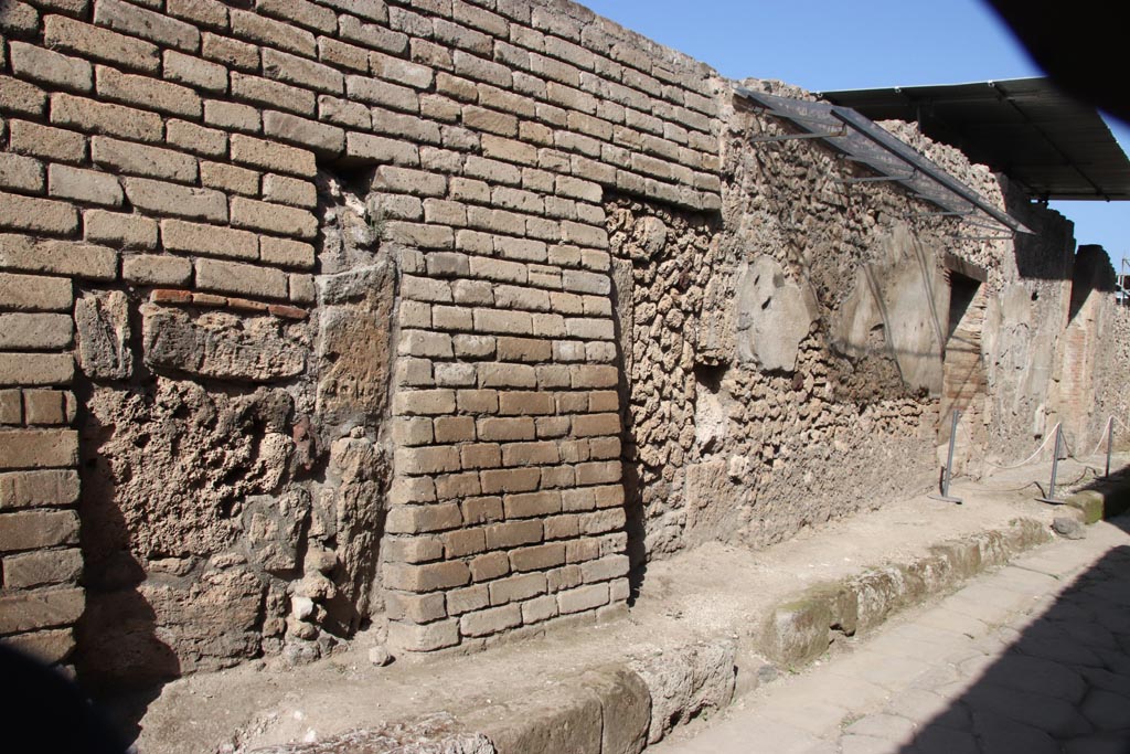 V.7.5 in centre, Pompeii. October 2023. Looking east along north side, with doorway V.7.6, on right. Photo courtesy of Klaus Heese.