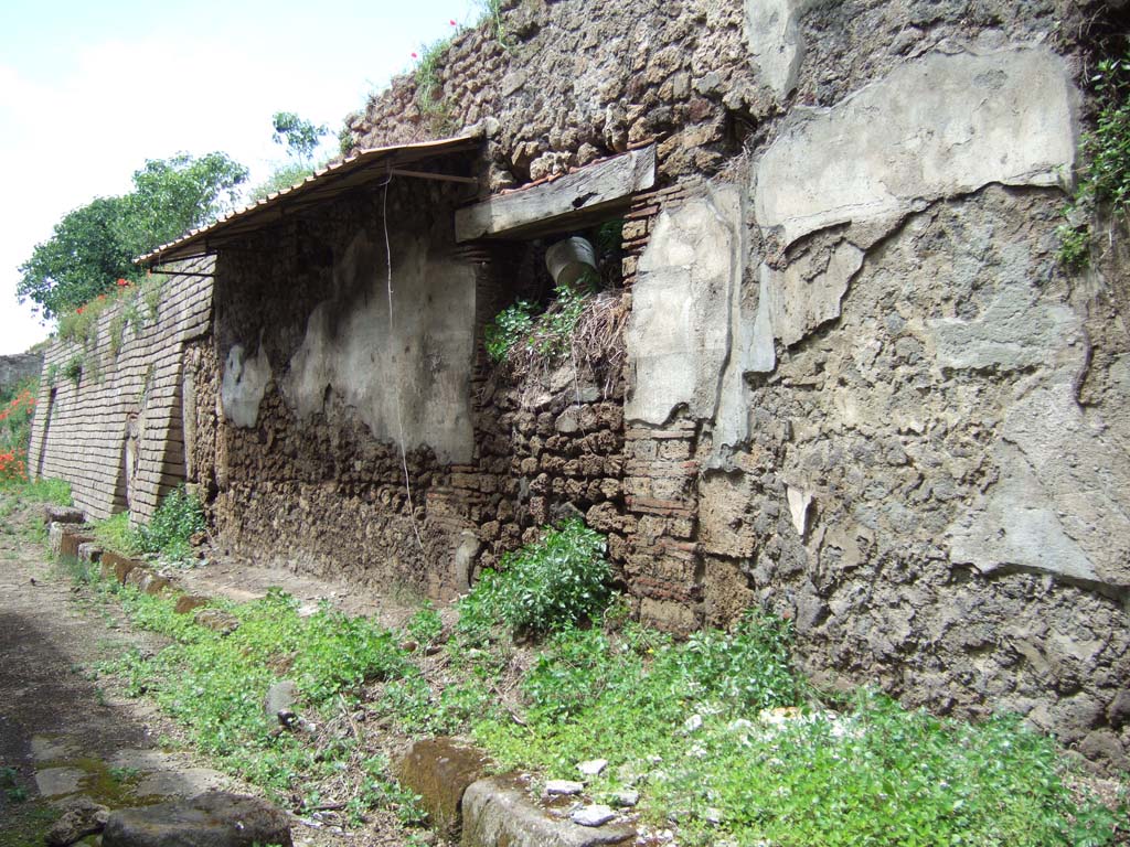 V.7.5 and V.7.6 Pompeii. May 2006. 
Entrance doorways on either side of painted plaster with graffiti. Looking north-west along Vicolo delle Nozze d’Argento.

