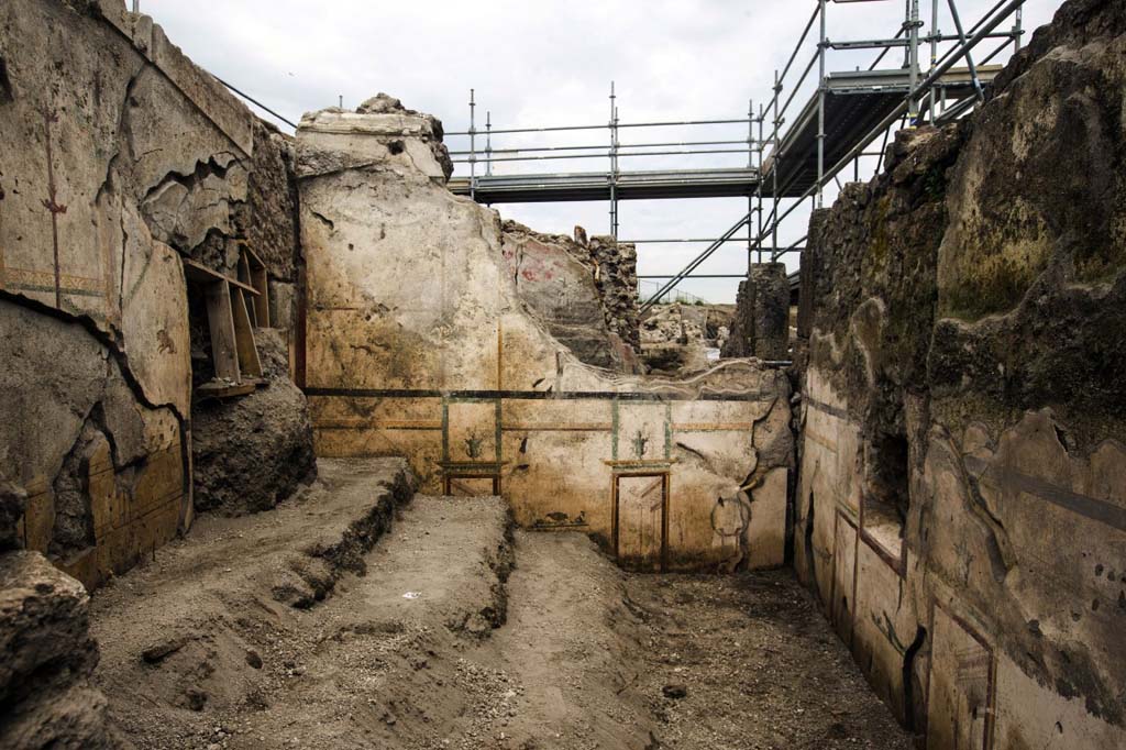 V.7.7 Pompeii. 2018. To the west of the entrance a room was investigated in which it is possible to recognize an older fresco decoration, later covered with a richer fourth-style decoration. 
It is possible that the oldest decoration is prior to the earthquake of 62, while the last decoration refers to renovations following this event.
Photograph © Parco Archeologico di Pompei.