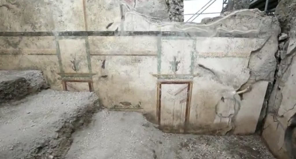 V.7.7 Pompeii. 2018. Room to the west of the entrance, east wall with architectural scenes with urns placed on top.
Photograph © Parco Archeologico di Pompei.