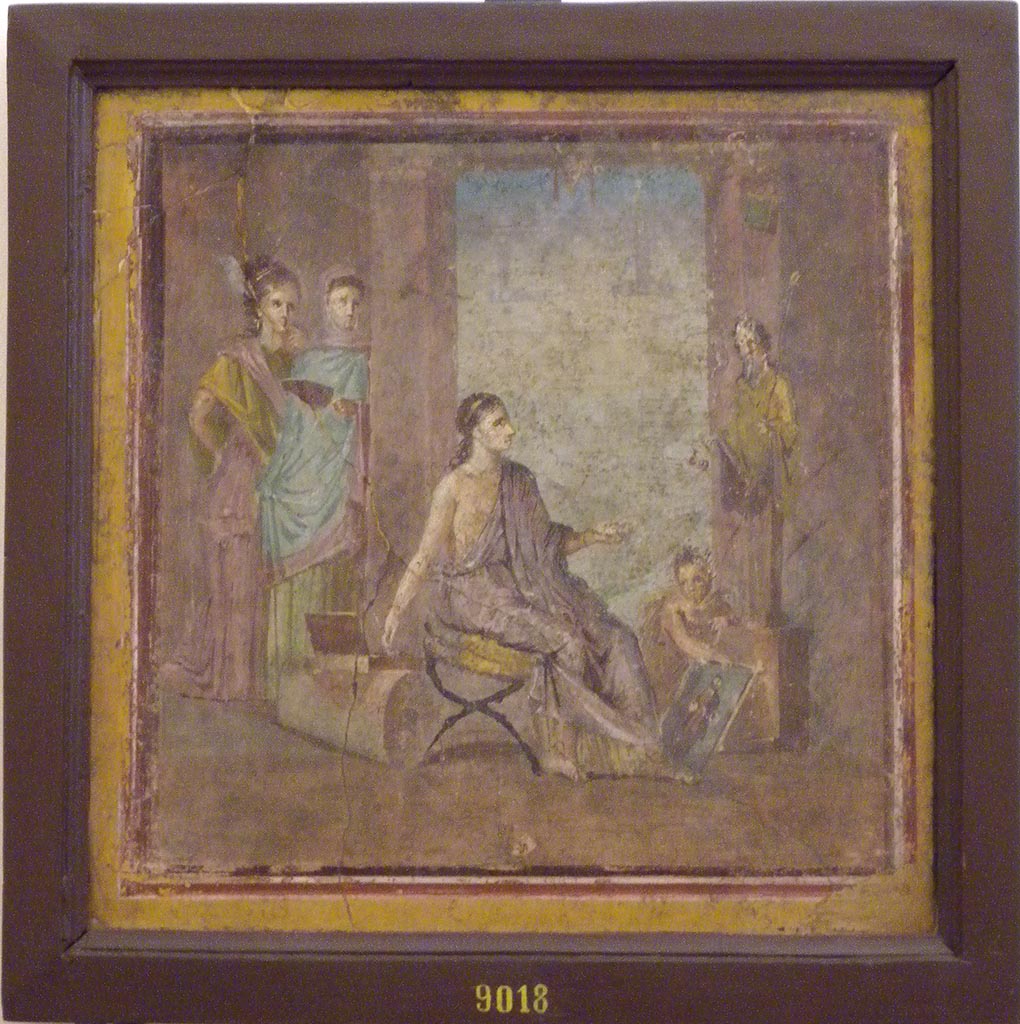 VI.1.10 Pompeii. December 2007. Found 22nd June 1771 on east wall of room 9, room to south of garden.  
Wall painting of a young woman painting a herm of Dionysus.
A cupid is holding the unfinished picture while she mixes colours on her palette. 
Two other maidens are watching the artist with unfeigned interest.
See Mau, A., 1907, translated by Kelsey F. W. Pompeii: Its Life and Art. New York: Macmillan.  (pp. 280-2, T. 133).
Now in Naples Archaeological Museum. Inventory number 9018.