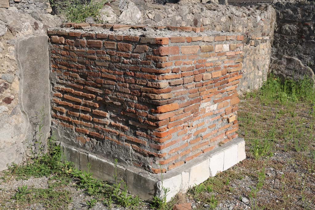 VI.1.13 Pompeii. December 2018. 
Looking towards north side of marble clad pedestal or statue base against east wall. Photo courtesy of Aude Durand.