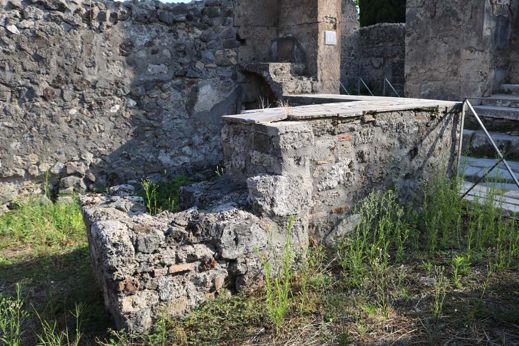 VI.1.18, Pompeii. December 2018. 
Looking south to two-sided marble counter with hearth and two-tier shelving. Photo courtesy of Aude Durand.