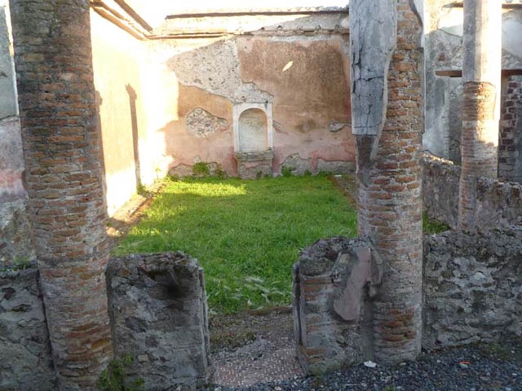 VI.2.22 Pompeii. May 2011. Looking south from north portico.
According to Boyce, standing in the centre of the south wall is a fine aedicula lararium (h.2.55).
Upon a rectangular base, painted red, a heavy projecting ledge adorned with triple bands of stucco ornament supports a platform (1.10 x 0.35, height above the floor 0.75), upon which rest the bases of two tall, fluted columns (h.1.30) with bases and capitals – all coated with white stucco.
The columns in turn support a pediment, the tympanum of which is surrounded by a double cornice of stucco relief.
The back wall within the aedicula is hollowed out to form a shallow semi-circular niche, and painted blue.
See Boyce G. K., 1937. Corpus of the Lararia of Pompeii. Rome: MAAR 14, (p.44, no.142, Pl.5,2)
See Giacobello, F., 2008. Larari Pompeiani: Iconografia e culto dei Lari in ambito domestico. Milano: LED Edizioni, (p.269 no.V41)