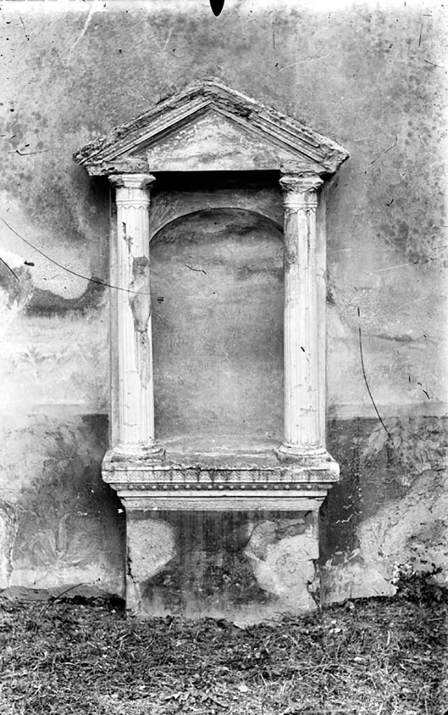 VI.2.22 Pompeii. W.1392. Aedicula niche lararium.
According to Boyce, in the centre of the south wall of the pseudoperistyle stands a fine aedicula.
On a rectangular base painted red, a heavy projecting ledge adorned with triple bands of stucco supported a platform.
On this platform rested the bases of two tall, fluted columns with bases and capitals, all coated with white stucco.
The columns in turn supported a pediment.
The back wall within the aedicula is hollowed out to form a niche, and painted blue.
See Boyce G. K., 1937. Corpus of the Lararia of Pompeii. Rome: MAAR 14. (p.44, and Pl.35,2) 
Photo by Tatiana Warscher. Photo © Deutsches Archäologisches Institut, Abteilung Rom, Arkiv.
