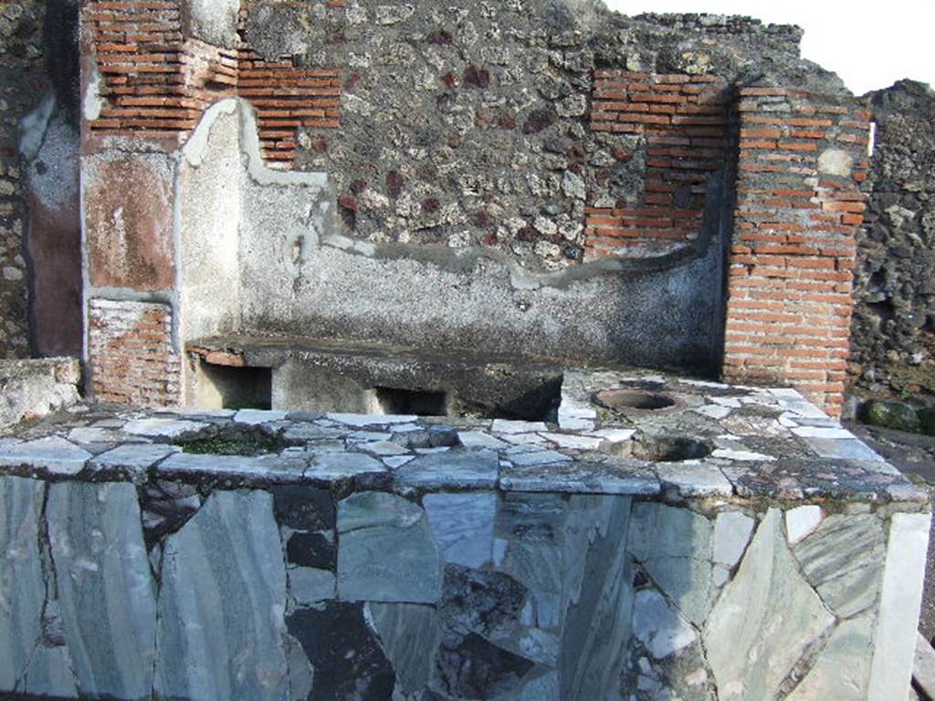 VI.3.20 Pompeii.  December 2005. Looking east across counter. According to Breton:
This bar of Fortunata had a counter of masonry which held several large terracotta containers, and was covered with a marble tablet, where the footprints of cups/glasses could still be recognised. 
The liquids contained in them must have contained some acid principle which had attacked the polish of the marble. 
At the rear was a higher area which held the brazier for heating various beverages.”
See Breton, E., 1855. Pompeia, decrite et dessine, (p.219)