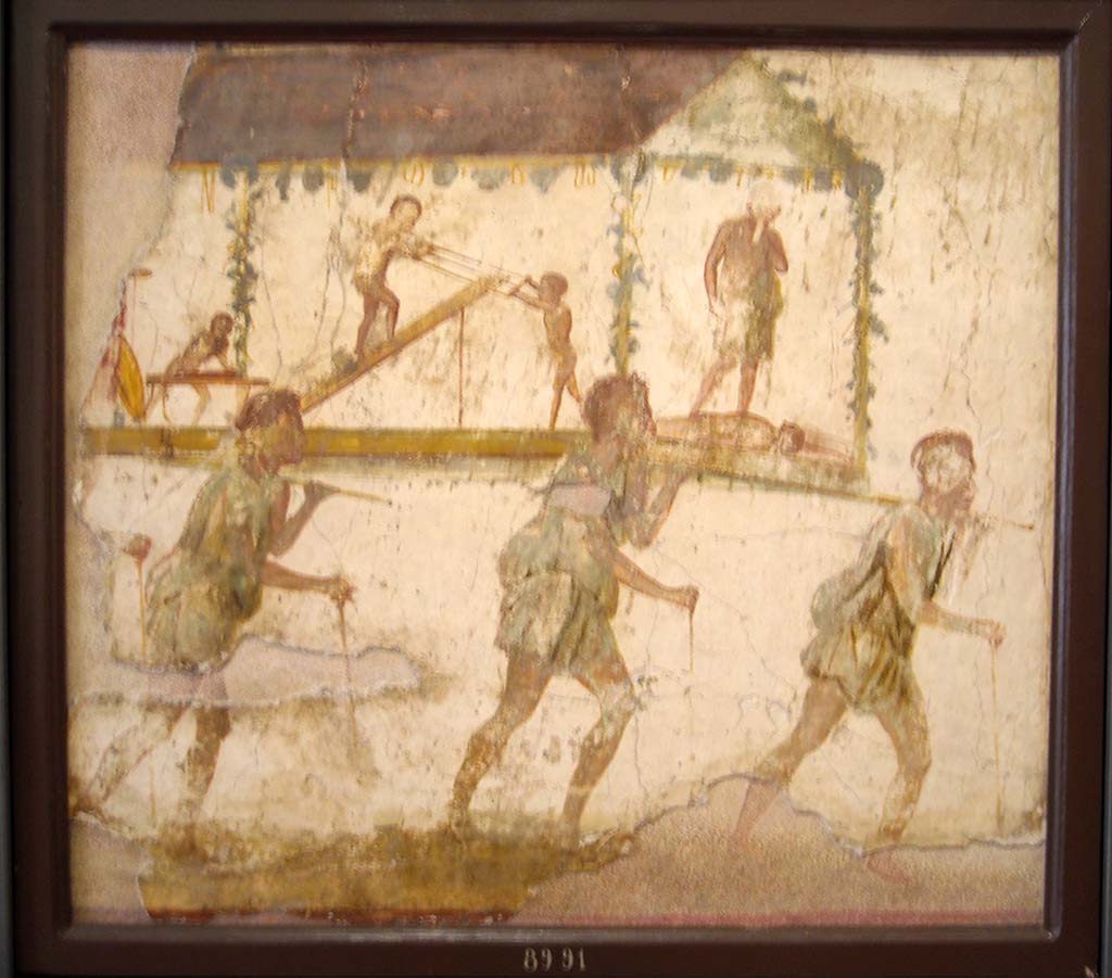 VI.7.9 Pompeii. Wall painting of the Procession of the Carpenters.   
Originally found on pilaster between entrances VI.7.8 and VI.7.9.
Now in Naples Archaeological Museum. Inventory number 8991.
See Helbig, W., 1868. Wandgemälde der vom Vesuv verschütteten Städte Campaniens. Leipzig: Breitkopf und Härtel. (1480).
According to Leach, figures of Minerva, Mercury and Daedalus painted on its exterior pilasters (6.7.8-12), as well as another painting of a procession advertising the craft of Daedalus under the protection of Minerva and Mercury, were taken by Mau as an indication that this was a Carpenter’s workshop.
The sign showed 3 carpenters bearing a ferculum (bier or litter) that included a figure of Daedalus and some workmen performing carpenters’ tasks.  
A dead figure lies before Daedalus' feet: this may well be a reference to the nephew Perdix whom the legendary artisan murdered through jealousy for his invention of the rake.  
(PPM 4, p389-91, however, suggested that the sign indicated a perfumer’s shop that dealt in spices requisite to funeral rituals).
See Leach, E.W: The Social Life of Painting in Ancient Rome and on the Bay of Naples.