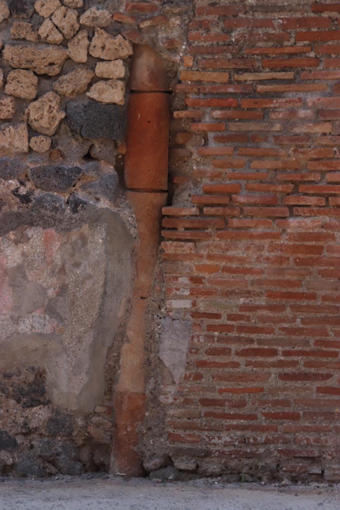 VI.7.10 Pompeii. October 2022. 
Downpipe on south side of entrance doorway, between VI.7.9 and 10, in front façade. 
Photo courtesy of Klaus Heese.