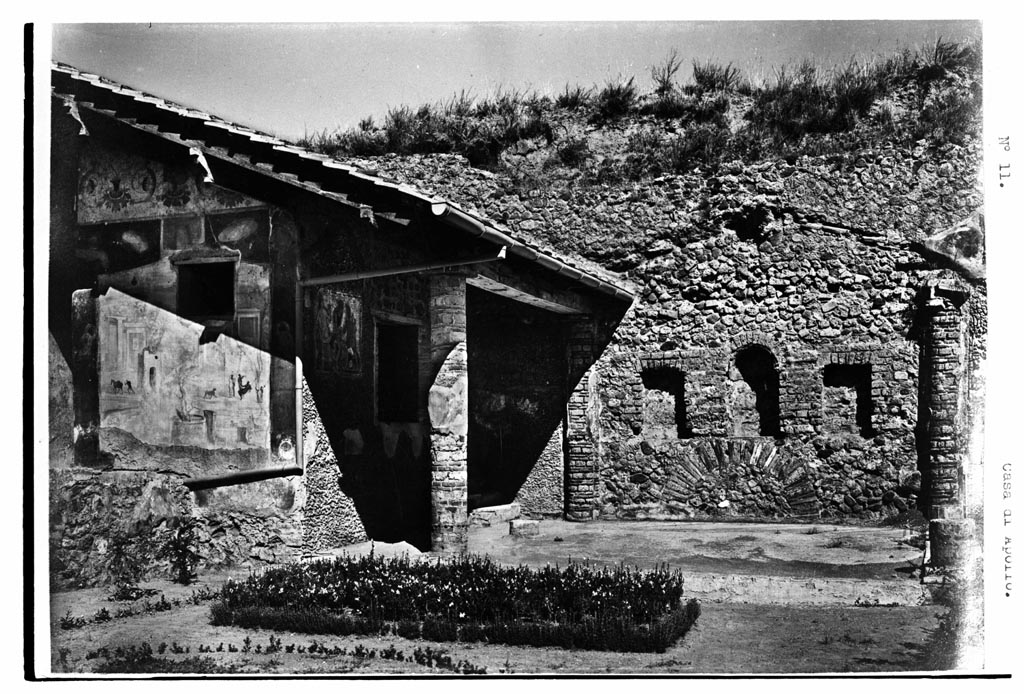 VI.7.23 Pompeii. W.1585. Looking north across garden to summer triclinium.
Photo by Tatiana Warscher. Photo © Deutsches Archäologisches Institut, Abteilung Rom, Arkiv.
According to Soprano –
Ubicazione: xystus.
Bibliog. Fiorelli, op. c., p.115; Breton, op. c., p.275; Dyer, op. c., p.391.
In fondo allo xystus appare uno spazio rettangolare con pavimento a mosaico e tettoia a doppio spiovente, sorretta da due semi-colonne addossate al muro di fondo e da quattro colonne.  Di queste esistono solamente le due del lato occidentale, ricostruite per il restauro della tettoia.
Sul muro di fondo si aprono tre nicchie, la centrale absidata e le due laterali rettangolari. 
Completamente privi di intonaco sono le nicchie e il muro di fondo che pero era rivestito, come le colonne, di marmo nella parte inferiore e di pasta vitrea policroma e di conchiglie nella parte superiore.
Il mosaico del pavimento e oggi completamente distrutto.
See Soprano, P. (1950). I triclini all’aperto di Pompei. (In Pompeiana, raccolta di studi per il secondo centenario degli scavi di Pompei. Napoli, Gaetano Macchiaroli, Editore, p.308, no.33.
According to Jashemski –
At the rear (north end) of the garden were four columns and two engaged columns, covered with blue-grey marble to a height of 0.20m., some with traces of mosaic and shells preserved above. Between the two engaged columns on the north wall was a round-headed niche with a rectangular niche on either side. The latter were at least partly lined with marble, and there is still some blue mosaic in the centre niche. The wall was covered with pumice.  …….etc.
Most scholars believe that the columns supported a pergola, but beyond that there is little agreement. Fiorelli and Soprano believed that the pergola once shaded a garden triclinium. Breton, Fiorelli and Warscher believed that the niches held the statues of deities. Sear believed that it was a nymphaeum, but Neuerburg does not include it in his catalogue of the fountains and nymphaea of ancient Italy. No water pipes are reported, not any indications of a fountain, such as a basin below, as in the garden of the house of the Little Bull (V.1.7). The area between the columns is said to have had a mosaic pavement, but nothing of it remains today. Professor Richardson suggested to me that a mosaic pavement would not have been completely exposed to the elements, and that it may have been roofed with thatch, or possibly with canvas.
See Jashemski, W. F., 1993. The Gardens of Pompeii, Volume II: Appendices. New York: Caratzas. (p.132).