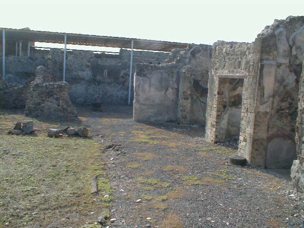 VI.9.5 Pompeii. September 2004. 
Looking south across west portico of Corinthian atrium 16, towards the remains of the area of a pseudo-peristyle 19, ahead.
On the right is the east end of the room 14 the entrance corridor, followed by a doorway to a cubiculum, room 17 and oecus, room 18.