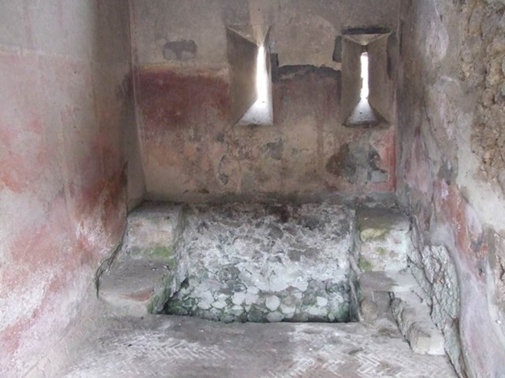 VI.9.6 Pompeii. March 2009. Room 18, large latrine near east wall of kitchen and latrine. According to Hobson, this latrine is just over one metre wide and would have had more than one seat. This would allow for “private” socialisation. See Hobson, B., 2009. Latrinae et foricae: Toilets in the Roman World. London; Duckworth. (p.80) He also states that this latrine possibly would have seated two or three persons.  It had a high decorated dado, painted red, with yellow panels but without motifs. In the area above the dado, a garland of flowers is visible. The floor is a mixture of herringbone and oval tiling. See Hobson, B., 2009. Latrinae et foricae: Toilets in the Roman World. London; Duckworth. (p.86 and fig.110)