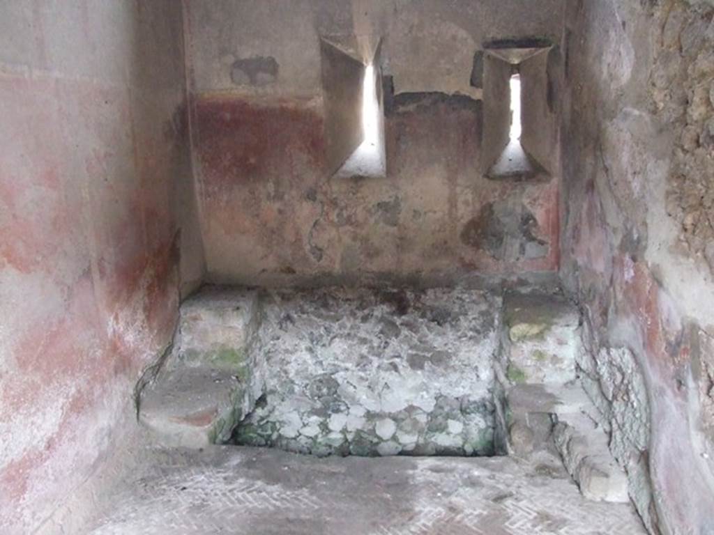 VI.9.6 Pompeii. March 2009. Room 18, large latrine near east wall of kitchen and latrine. According to Hobson, this latrine is just over one metre wide and would have had more than one seat. This would allow for “private” socialisation. See Hobson, B., 2009. Latrinae et foricae: Toilets in the Roman World. London; Duckworth. (p.80) He also states that this latrine possibly would have seated two or three persons.  It had a high decorated dado, painted red, with yellow panels but without motifs. In the area above the dado, a garland of flowers is visible. The floor is a mixture of herringbone and oval tiling. See Hobson, B., 2009. Latrinae et foricae: Toilets in the Roman World. London; Duckworth. (p.86 and fig.110)