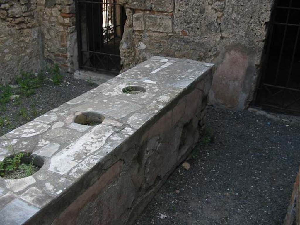 VI.10.1 Pompeii. May 2003. Marble counter with three urns. Looking towards the east wall, the door on the left leads into the room on the north side (also see VI.10.19).
The doorway on the right leads into the room on the south side of the bar, and probably originally linked to VI.10.2 Photo courtesy of Nicolas Monteix.