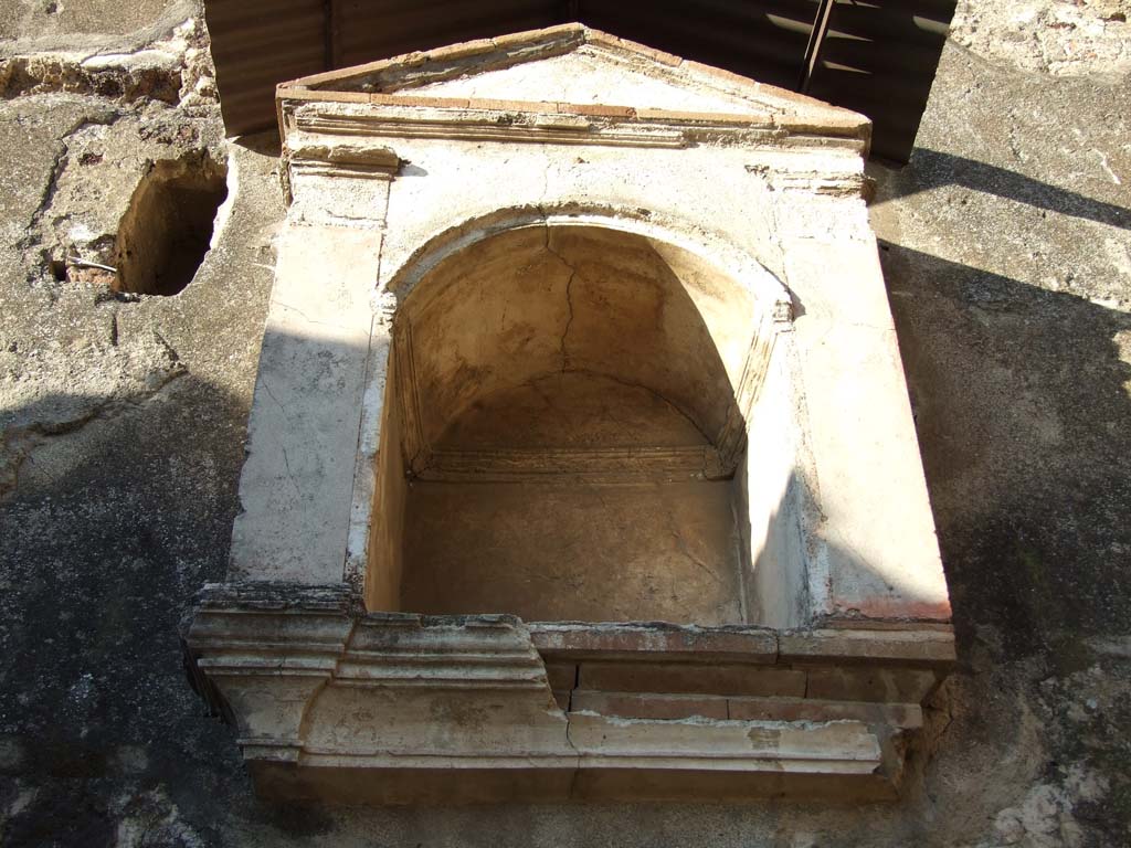 VI.12.2 Pompeii. December 2006. North wall of Kitchen, arched niche lararium with aedicula façade.
According to Boyce, there was a heavy and well-made aedicula façade with two red pilasters supporting a simple pediment. 
Inside the niche and around the curve was a modelled stucco cornice. 
Within the niche there stood a small terracotta altar.
See Boyce G. K., 1937. Corpus of the Lararia of Pompeii. Rome: MAAR 14. (p.52, 190, Pl. 5, 2).
(PPM – room 24)