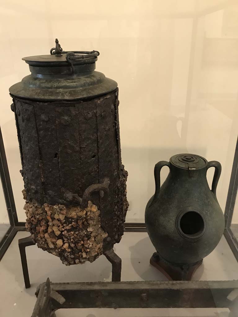VI.12.5 Pompeii. April 2019. Iron stove with bronze lid, on left. 
Found in VI.12.2/5 on 21st March 1831 in a room around the atrium of the four columns (VI.12.5)
Now in Naples Archaeological Museum. Inventory number 264932.
See Fiorelli G., 1862. Pompeianarum antiquitatum historia, Vol. 2: 1819 - 1860, Naples, p. 249
Photo courtesy of Rick Bauer.