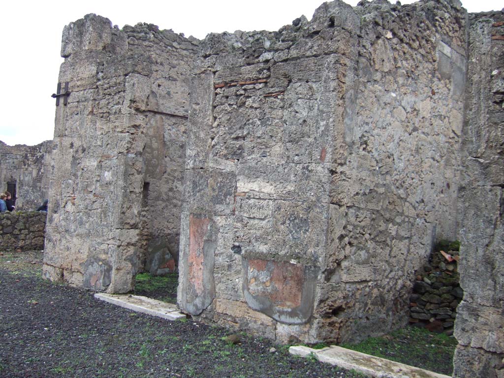VI.13.6 Pompeii. December 2005. Rooms on east side of the atrium. 
The doorway to a cubiculum is on the left, this would be the one where paintings were found on the walls but left in situ, and now lost.
According to Presuhn, “in a cubiculum on the right side of the atrium, was a wall painting also well preserved, showing Venus and Adonis, favoured subject of Pompeian painters (Helbig 331). Many paintings found in this house were taken to the Naples Museum, but others were left, and are now destroyed”.
See Presuhn, E. Pompei les dernières fouilles de 1874-75.
According to PPM –
«In the north wall in the north-west corner is a doorway into the east ala : the red zoccolo painted with panels with plants was edged from the yellow middle zone by a carpet-border with triangles by a white band. The upper cornice of moulded stucco was blue, with a white upper area.
There was no shortage of figurative subjects completely lost and documented only by Fiorelli's brief descriptions (Fiorelli, Descrizioni, p.424) – a Satyr with a Bacchante, Leda with the swan, Adonis sitting on the lap of Venus, accompanied by three cupids.”
See Carratelli, G. P., 1990-2003. Pompei: Pitture e Mosaici. V (5). Roma: Istituto della enciclopedia italiana, (p.165).